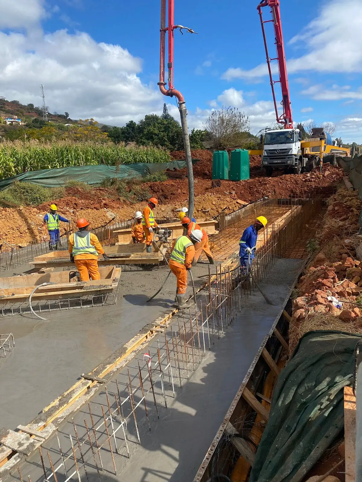 Workers pouring concrete into a foundation trench